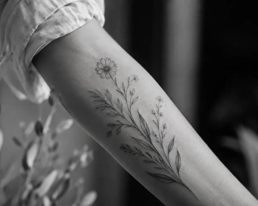 Tattoo ideas featuring a fine-line botanical flower design on the arm