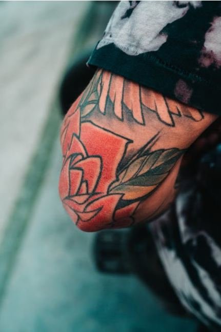 Bold red rose in the american traditional tattoo style on a bicep