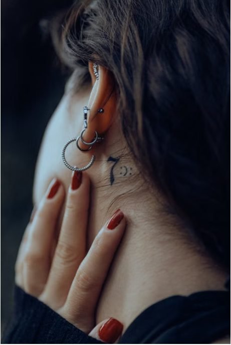 Behind the ear tattoo healing — close-up of a small tattoo behind a person's ear showing the healing skin and placement near the hairline