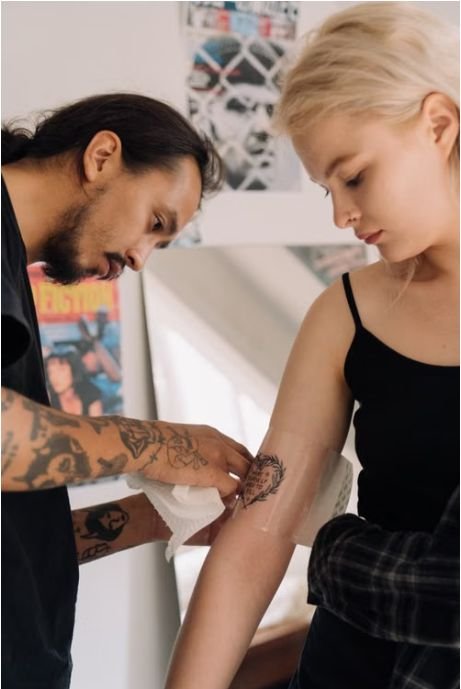 Tattoo artist wrapping a fresh tattoo on a client's arm with second skin film