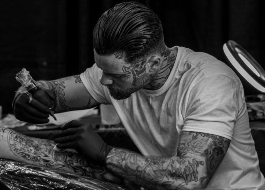 Least painful places to get a tattoo — black and white close-up of a tattoo artist working