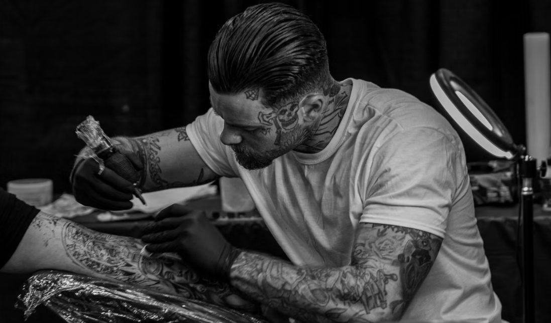 Least painful places to get a tattoo — black and white close-up of a tattoo artist working