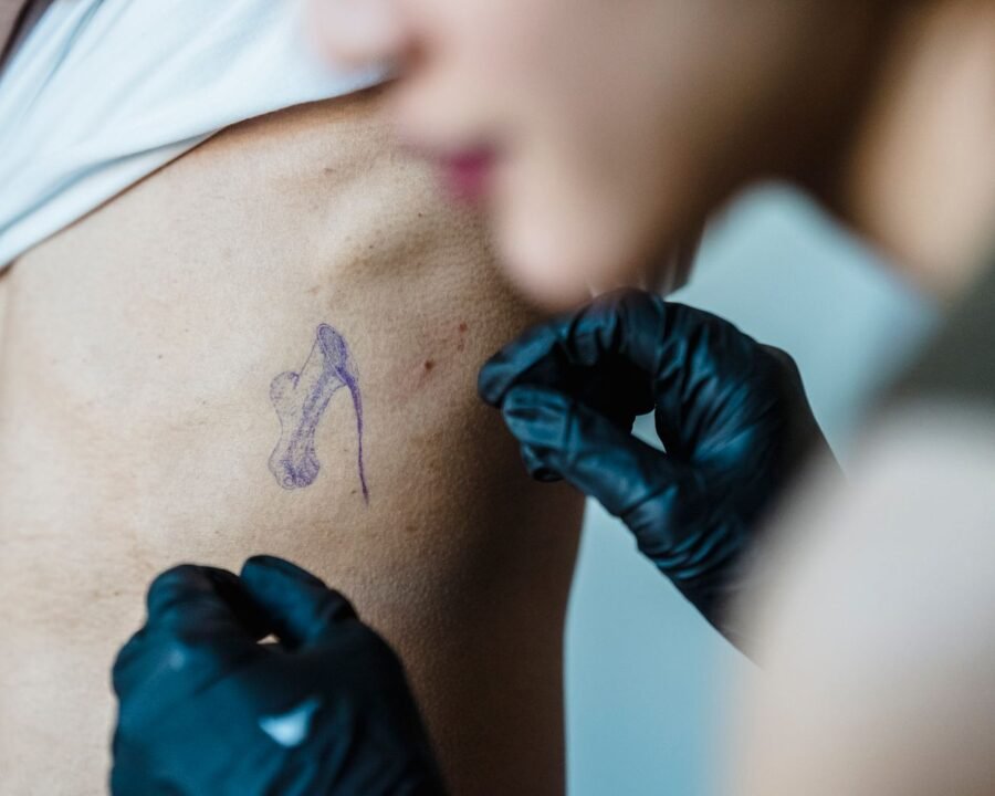 Tattoo artist applying a stencil to a client’s ribs, one of the most painful tattoo spots
