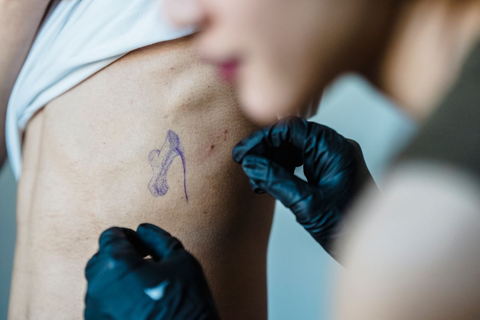 Tattoo artist applying a stencil to a client’s ribs, one of the most painful tattoo spots