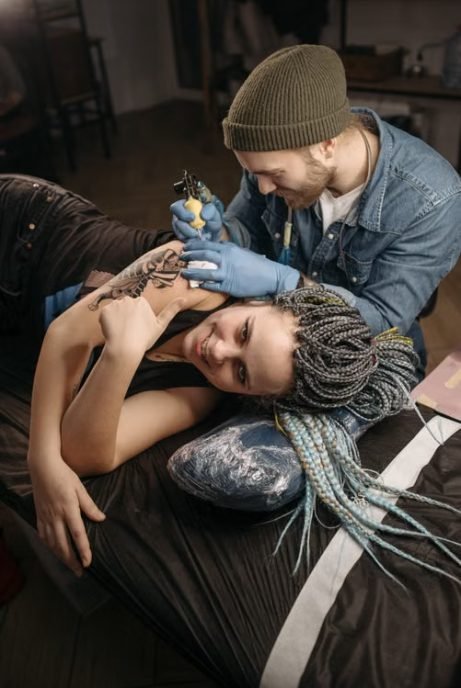 Shoulder tattoo pain — close-up of a tattoo being applied to someone's shoulder and shoulder blade area in a tattoo studio
