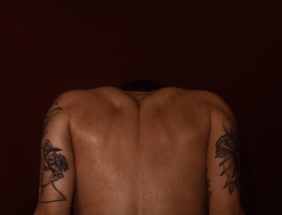 Spine tattoo pain — close-up of a fine-line tattoo running down the spine, showing the thin skin over the vertebrae