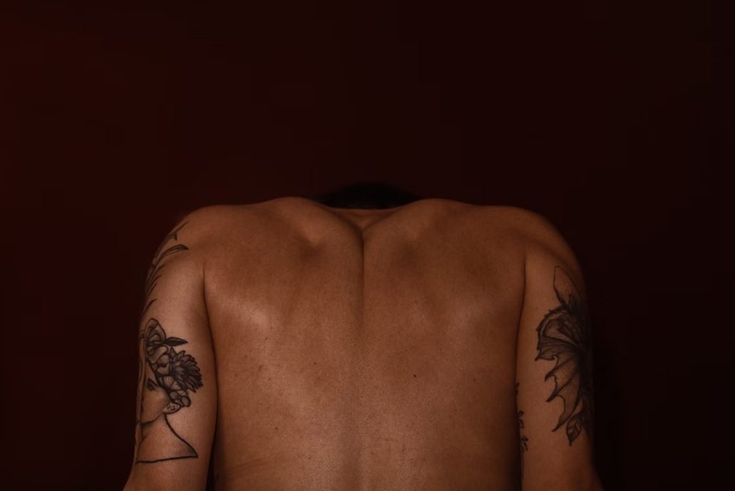 Spine tattoo pain — close-up of a fine-line tattoo running down the spine, showing the thin skin over the vertebrae