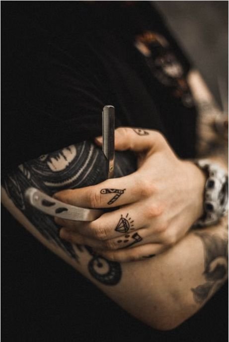 Close-up of a tattooed arm holding a straight razor